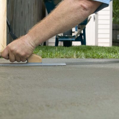 Person screeding wet cement in a backyard project - CA Plasterers